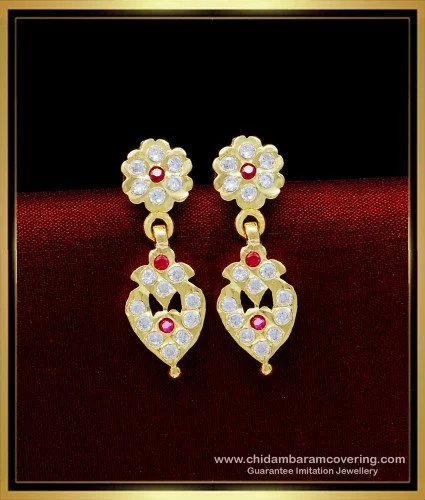 Premium Photo | A pair of gold earrings with a red stone on the left side.